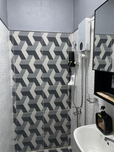 a bathroom with a sink and a tiled wall at Goldland Caelestis Guest House in Bacolod