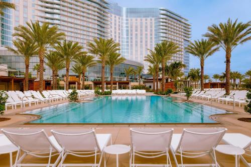 a pool with chairs and palm trees and a building at Gaylord Pacific Resort & Convention Center in Chula Vista