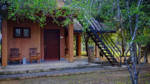 a house with two chairs and a staircase in front of it at Jungle Edge Home Sigiriya in Sigiriya