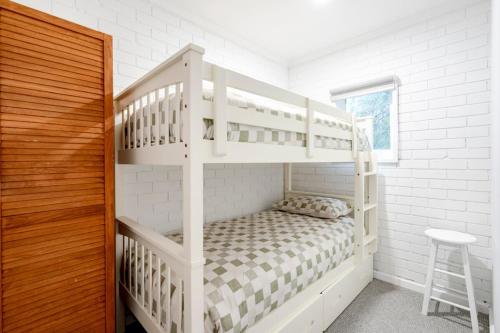 a bedroom with white bunk beds and a stool at The River Nook on Hurst in Ocean Grove