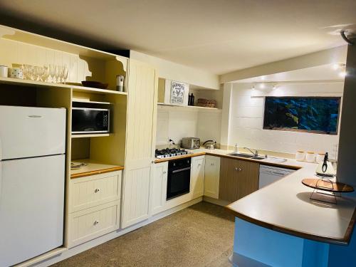 a kitchen with white cabinets and a white refrigerator at Peninsula Paradise in Tauranga