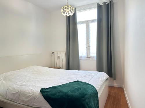 - une chambre avec un lit et une fenêtre ornée d'un lustre dans l'établissement Dahlias- 6 pers Vrai tout à pied, à Saint-Raphaël