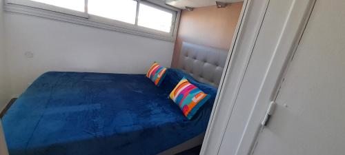 - une petite chambre avec un lit bleu et 2 oreillers dans l'établissement Appartement 78, PORT NATURE colline 2 au village naturiste, au Cap d'Agde