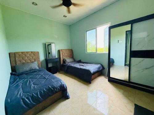 a bedroom with two beds and a ceiling fan at Homestay Adam's Nur in Marang