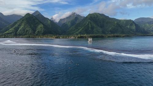 an aerial view of a beach with mountains in the background at Hava'e Lodge TEAHUPOO in Teahupoo