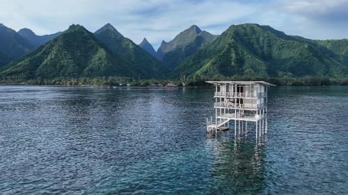 a tower in the middle of a lake with mountains at Hava'e Lodge TEAHUPOO in Teahupoo