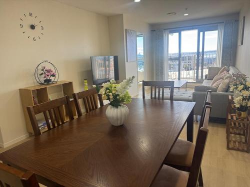 a dining room table with a vase of flowers on it at Luxury Penthouse 2 bd 2 bth 2 carparks Pool in Auckland