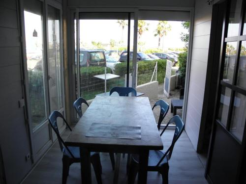 - une table et des chaises en bois dans une chambre avec fenêtres dans l'établissement Appart avec cour Gruissan Grazel, à Gruissan