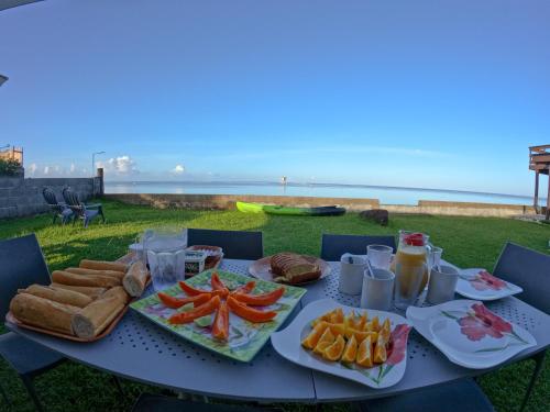 una tavola con cibo sopra con l'oceano sullo sfondo di Hava'e Lodge TEAHUPOO a Teahupoo
