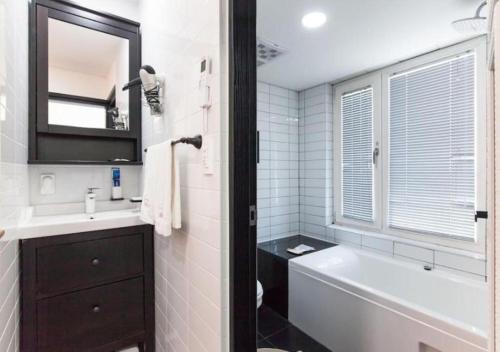 a bathroom with a tub and a sink and a mirror at HANI Haus in Jeju