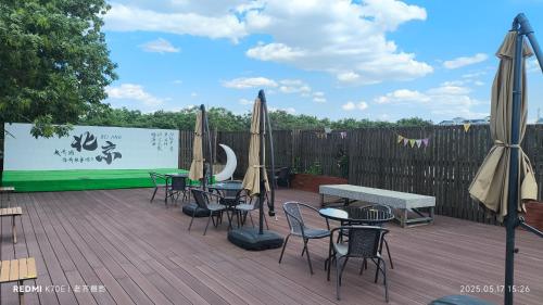 a deck with tables and chairs and umbrellas at YOYO PINKE Hotel in Beijing