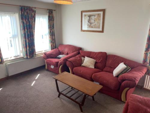 a living room with two red couches and a table at Causeway holiday home in Ballycastle