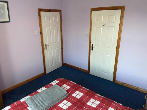 a bedroom with two doors and a bed with a quilt at Causeway holiday home in Ballycastle