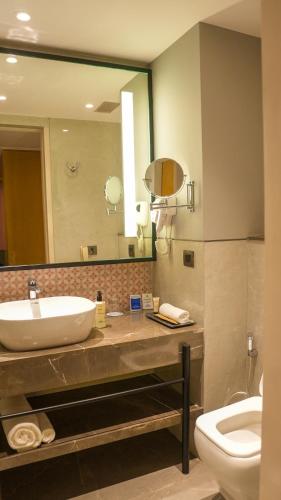 a bathroom with a sink and a toilet and a mirror at Sarovar Portico Birgunj in Bīrganj