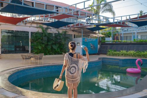 a woman standing in front of a swimming pool at Perfectstayz Koko Maya 5 mins walk to beach in Morjim