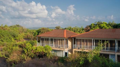 a building with a brown roof on top of trees at Perfectstayz Koko Maya 5 mins walk to beach in Morjim