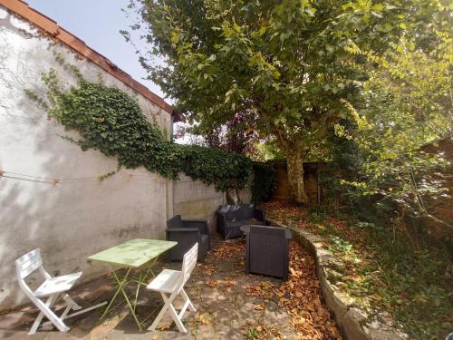 d'une terrasse avec une table, des chaises et un arbre. dans l'établissement Studio avec jardin, à Talence