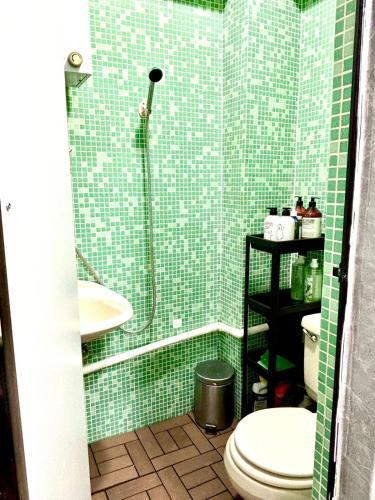 a green tiled bathroom with a toilet and a shower at Cozy Bachelor In PmQ with Rooftop in Hong Kong