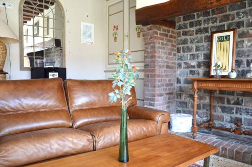 Ouville-la-RivièreにあるL'Orée des Prés - Gîte familial - 4 étoiles - 8 personnesの茶革のソファーとテーブル
