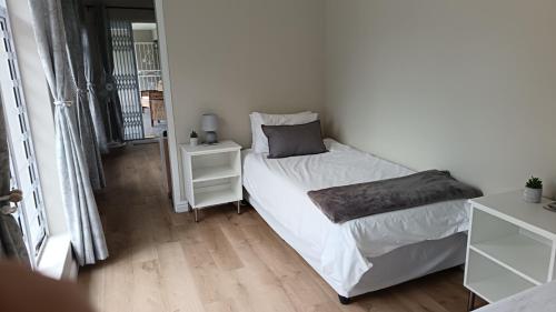 a small bedroom with a bed and a night stand at Lily Lane in Gqeberha
