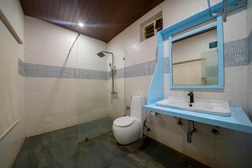 a bathroom with a sink and a toilet and a mirror at Perfectstayz Koko Maya 5 mins walk to beach in Morjim