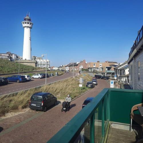 a man walking a bike next to a lighthouse at Torenlicht - Zand I (36) in Egmond aan Zee