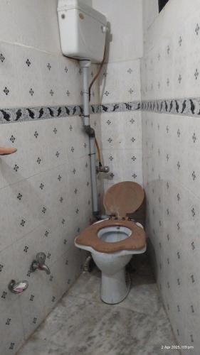 a bathroom with a toilet with a wooden seat at PandeGuestHouse in Almora