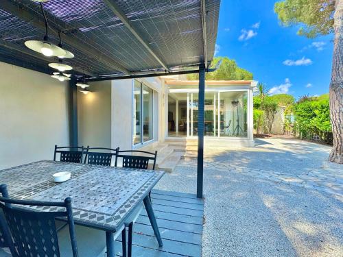 un patio avec une table et des chaises devant une maison dans l'établissement L'Écrin de la Pinède, Villa, Piscine,Climatisation, au Cap d'Agde