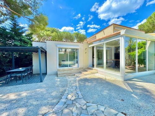 une maison avec des portes en verre et une terrasse dans l'établissement L'Écrin de la Pinède, Villa, Piscine,Climatisation, au Cap d'Agde