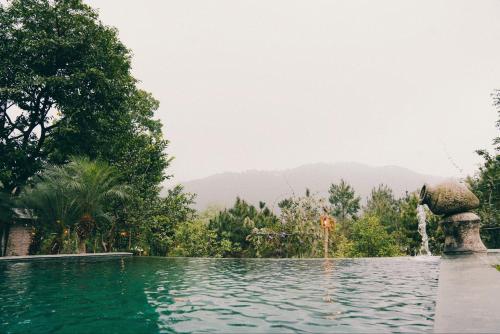 a pool at a resort with a fountain at Căn Bighomie in Sóc Sơn