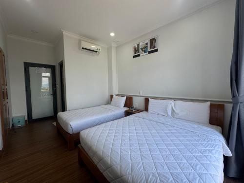 a hotel room with two beds and a window at Hotel Phạm Gia Phan Thiết in Phan Thiet