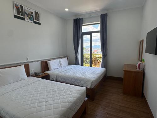 a hotel room with two beds and a window at Hotel Phạm Gia Phan Thiết in Phan Thiet