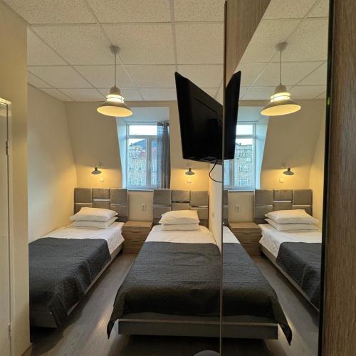 a room with three beds and a flat screen tv at Hotel Ticha in Shumen
