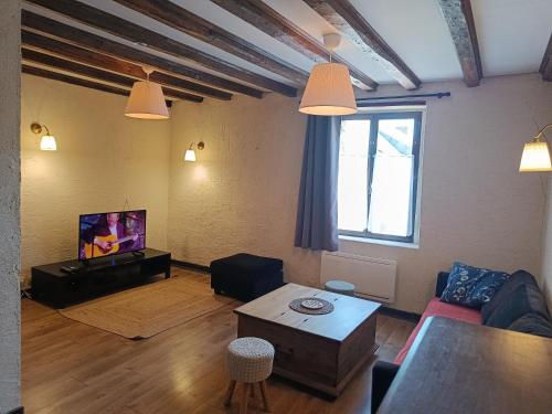 ein Wohnzimmer mit Couch und Fernseher in der Unterkunft Le Logis De Judicael in Paimpont