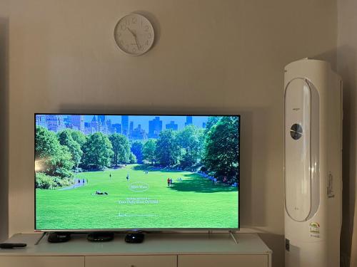 a flat screen tv sitting on a stand with a clock at Ilsan Goyang Stadium Staywell in Madu, kintex in Goyang
