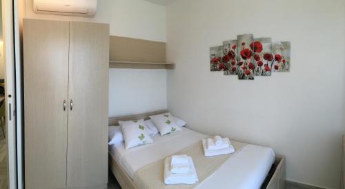 Habitación pequeña con cama y una pintura de flores. en SunSea, en Calatabiano
