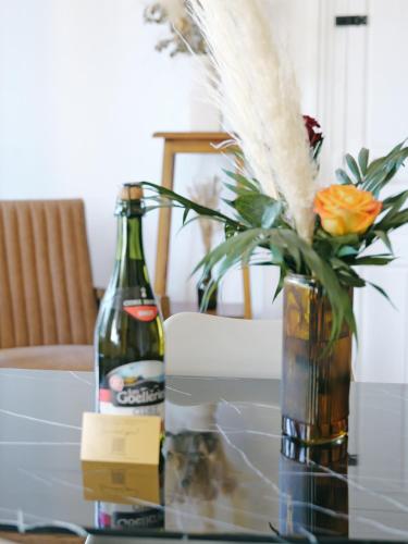 a glass table with a bottle and a vase with flowers at Hôtel Lefort - Balcon céleste in Guingamp