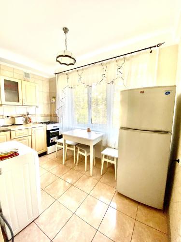 a kitchen with a white refrigerator and a table at 2-К институт сердця возле Метро Чернігівська in Kyiv