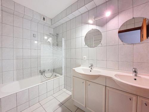 La salle de bains est pourvue de carrelage blanc, d'un lavabo et d'une baignoire. dans l'établissement DEUX APPARTEMENTS COMBINABLES - PROCHE REMONTEE MECANIQUES - MORZINE- 12 PERSONNES- ETOILE 1&2, à Morzine