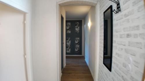un couloir avec un mur de briques blanches et une porte noire dans l'établissement Elégant Appartement T3 - 2 CHAMBRES - Netflix - Terrasse, à Castres