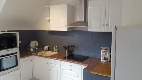 Il comprend une cuisine avec des placards blancs et un mur carrelé bleu. dans l'établissement Apartment close tonte sea, à Bénodet