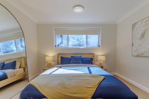 a bedroom with a large bed and a mirror at Wave and Willow Luxury Family Retreat in Jamberoo