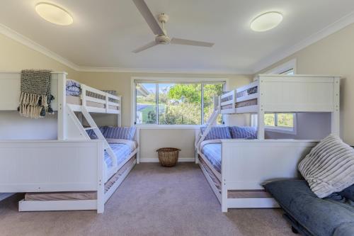 a bedroom with two bunk beds and a couch at Wave and Willow Luxury Family Retreat in Jamberoo