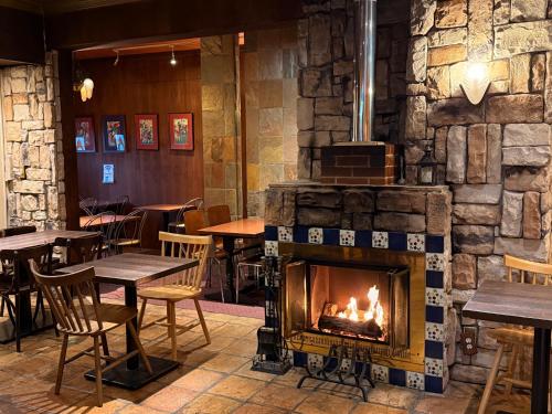 a fireplace in a restaurant with tables and chairs at Hotel Gasthof in Kagoshima