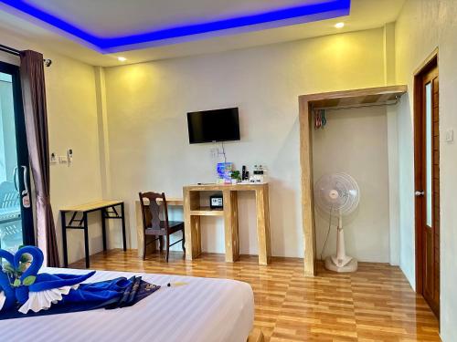 a hotel room with a bed and a desk and a tv at Maisuree Lanta Resort-Long Beach in Ko Lanta
