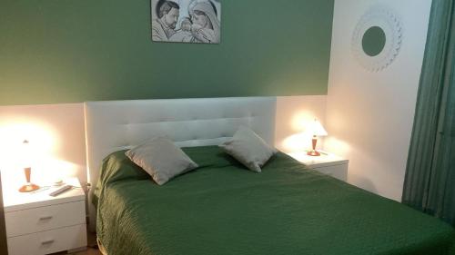 a bedroom with a green bed with two nightstands and two lamps at Villetta SCHIRÒ - BAGNASCO in Campofelice di Roccella