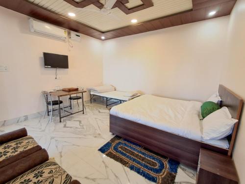 una camera da letto con un letto, un tavolo e una TV di LD Guest House, Ayodhya a Ayodhya