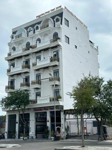 a large white building with balconies on a street at Hotel Phạm Gia Phan Thiết in Phan Thiet