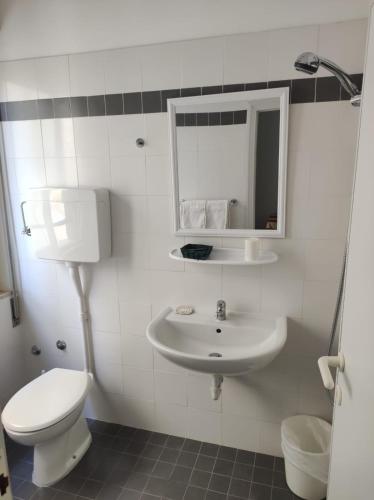 a white bathroom with a toilet and a sink at Hotel Diana in Misano Adriatico