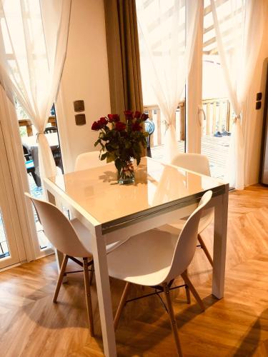 - une table à manger blanche avec des chaises blanches et un vase de fleurs dans l'établissement Mobil home, au Grau-dʼAgde